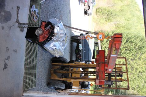 1979 Ford Bronco - An engine and transmission assembly is being lifted by a forklift, with a vehicle visible in the background.