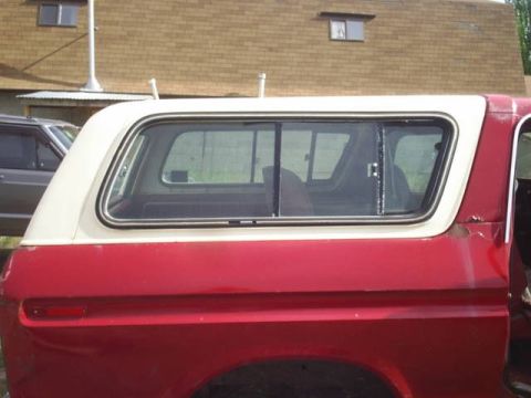 1979 Ford Bronco - The side profile of a red and white SUV is visible, with a portion of another vehicle to its left.