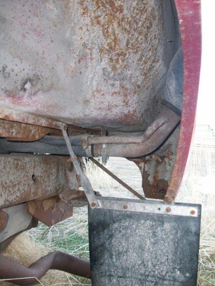 1979 Ford Bronco - The underside of a vehicle reveals a mud flap and rusted components, with a watermark indicating the source.