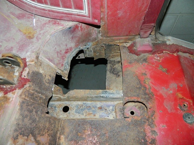 Heavily rusted interior floor pan with a large hole, showing structural damage
