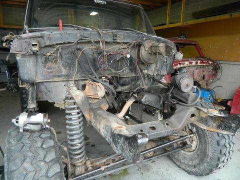 1979 Ford Bronco - Front end of a disassembled truck chassis, with another vehicle in the background.