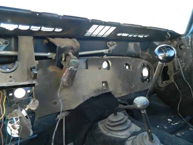 Interior shot of a vehicle's dashboard area, showing the steering column, shifter, and exposed wiring