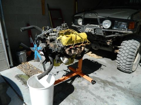1979 Ford Bronco - An engine is displayed on a stand in front of a white off-road vehicle.
