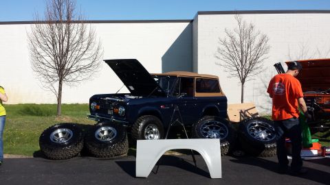 1995 Ford Bronco - A dark blue Ford Bronco is displayed with its hood open and spare tires around it, alongside a white fender.