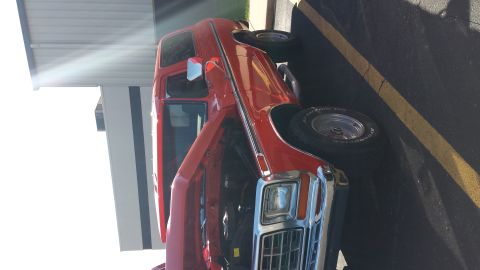 1995 Ford Bronco - This red pickup truck is parked with its hood open, revealing the engine bay.