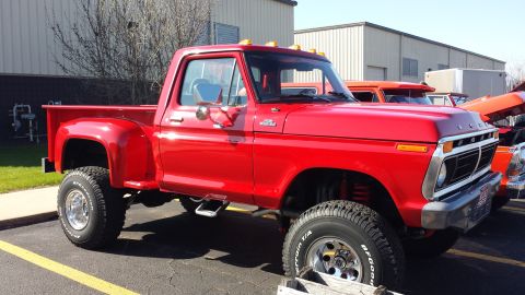 1995 Ford Bronco - This lifted red Ford F-Series pickup truck features off-road tires and a classic body style.