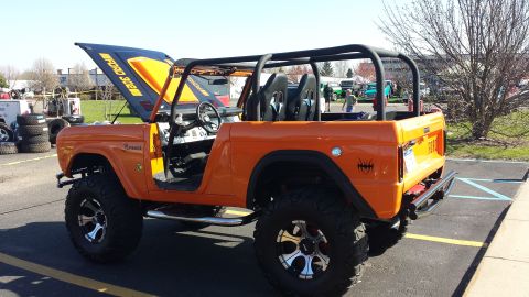 1995 Ford Bronco - This modified Ford Bronco features a roll cage and racing seats, with the hood open revealing engine details.