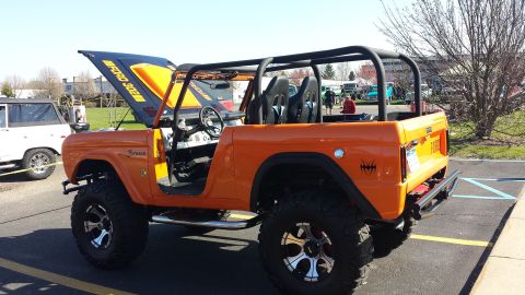 1995 Ford Bronco - This modified Ford Bronco features an open hood revealing "FORD 302" engine details and an aftermarket roll cage.