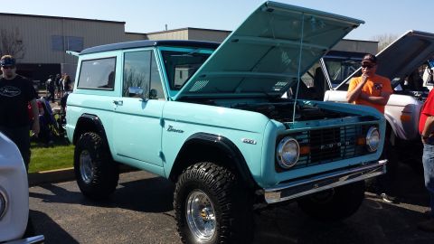 1995 Ford Bronco - A light blue Ford Bronco is displayed with its hood open at an outdoor event.