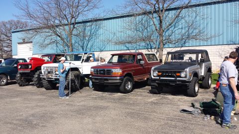 1995 Ford Bronco - Several modified Ford Broncos are lined up in a parking lot.