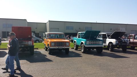1995 Ford Bronco - Several classic Ford Broncos are parked in a lot, including an orange model from 1975.
