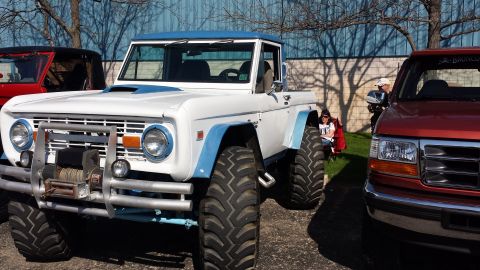 1995 Ford Bronco - Modified 1970s Ford Bronco with off-road tires and winch, parked next to other vehicles.