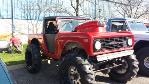 1995 Ford Bronco - This heavily modified Ford Bronco features a prominent hood scoop and oversized tires, parked outdoors.