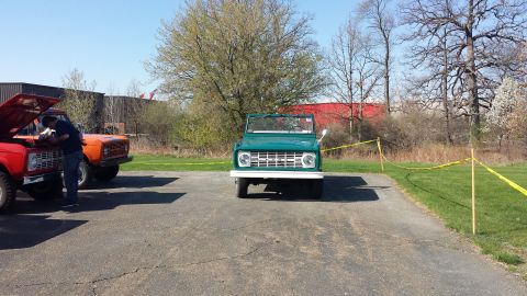 1995 Ford Bronco - A green first-generation Ford Bronco is parked in a lot, with two other Broncos visible to the left.
