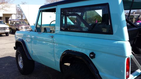 1995 Ford Bronco - This 1995 Ford Bronco is seen from the side with its hood open, parked next to other vehicles.