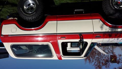 1995 Ford Bronco - This two-tone Ford Bronco features a red and white exterior, with a prominent Ford logo on the rear window.