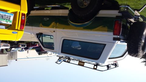1995 Ford Bronco - This 1995 Ford Bronco features a two-tone paint scheme and a roof rack, parked next to a yellow Ford Bronco.