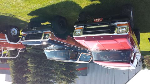 1995 Ford Bronco - Two classic Ford Broncos are displayed outdoors on a sunny day, with one a prominent light bar.