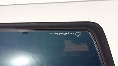 1995 Ford Bronco - A sticker on a vehicle's rear window displays a humorous message about a girlfriend's approval, accompanied by a thumbs-down icon.