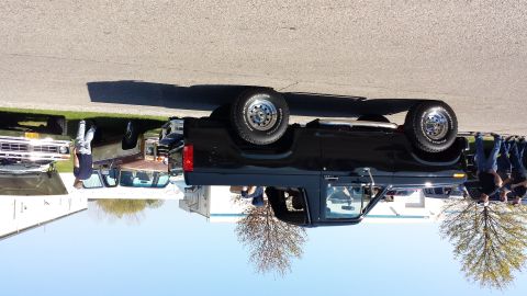 1995 Ford Bronco - Several vehicles are parked outdoors, including a black pickup truck with a spare tire on its rear.