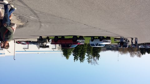 1995 Ford Bronco - A collection of trucks and vans are parked on a grassy area near a building under a clear blue sky.