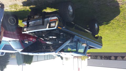 1995 Ford Bronco - A dark blue Ford truck, likely from the late 1970s, is parked on grass with its hood open.