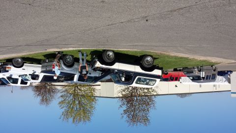 1995 Ford Bronco - Multiple SUVs are parked on the grass near a building. One appears to be a white Ford Bronco.