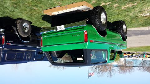 1995 Ford Bronco - A green 1978 Ford Bronco is parked next to a dark blue vehicle, with a spare tire on its tailgate.