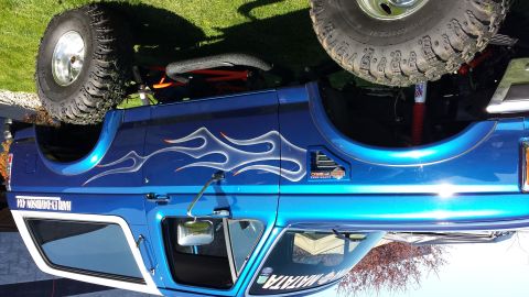 1995 Ford Bronco - This blue SUV features custom flame decals and a rear-mounted spare tire, with visible text on the side.
