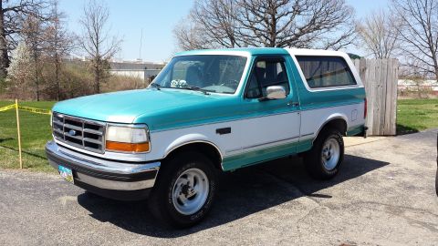 1995 Ford Bronco - This two-tone teal and white Ford Bronco is viewed from the front three-quarter angle.