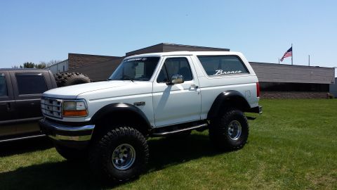 1995 Ford Bronco - White 1995 Ford Bronco lifted with off-road tires, parked next to another vehicle.