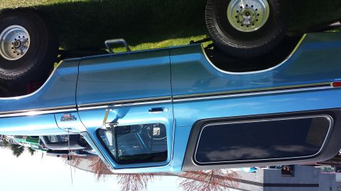 1995 Ford Bronco - This blue pickup truck has a distinctive body style and chrome accents, parked outdoors with other vehicles.