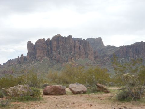 1995 Ford Bronco - A wide view of a rocky desert mountain range with scattered boulders and vegetation in the foreground.