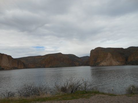 1995 Ford Bronco - A wide shot of a lake surrounded by mountains on a cloudy day, with a logo in the corner.
