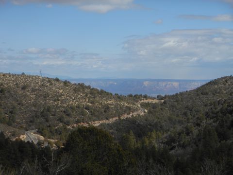 1995 Ford Bronco - A scenic view of a road winding through hills and trees, with distant mesas under a partly cloudy sky.