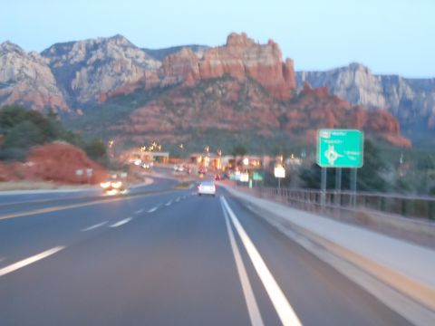 1995 Ford Bronco - Driving on a highway with traffic, approaching red rock mountains and a town.