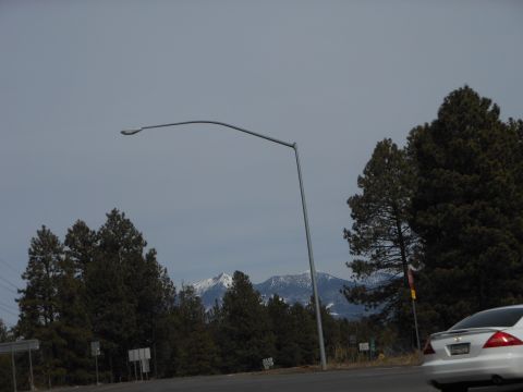 1995 Ford Bronco - A white sedan is seen from the rear on a road with trees and mountains in the background.