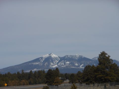1995 Ford Bronco - A scenic view of snow-covered peaks and evergreen trees under a hazy sky, with a road visible in the lower portion of the frame.
