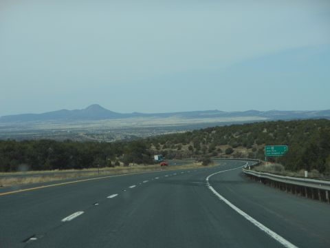 1995 Ford Bronco - A highway stretches towards distant mountains under a hazy sky, with a few vehicles on the road.