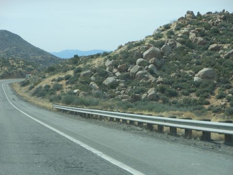 1995 Ford Bronco - A highway curves through a desolate, rocky landscape with sparse vegetation under a hazy sky.