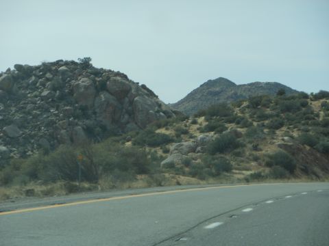 1995 Ford Bronco - View of a desert landscape with hills and a road, taken from a moving vehicle.