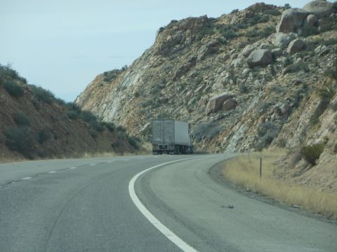1995 Ford Bronco - A semi-truck travels down a highway surrounded by , rocky terrain under a hazy sky.
