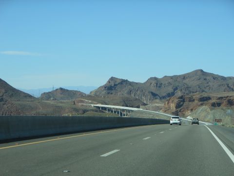 1995 Ford Bronco - A highway scene with two vehicles traveling through a mountainous landscape under a clear blue sky.