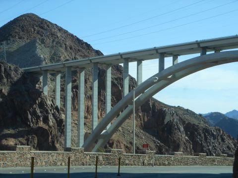 1995 Ford Bronco - A large concrete arch bridge spans a valley with mountains under a clear blue sky.