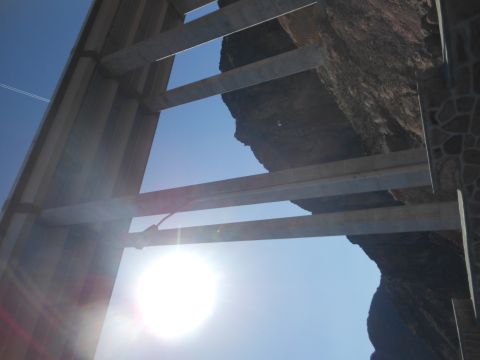 1995 Ford Bronco - The sun shines brightly through the framework of a bridge, illuminating a rocky cliff face.