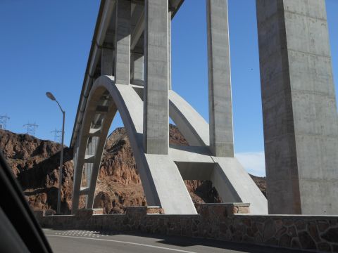1995 Ford Bronco - A large concrete bridge spans a roadway, with arid hills and power lines visible under a clear blue sky.