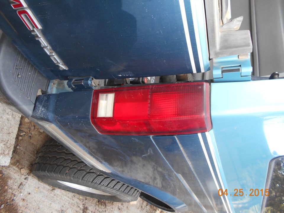 Rear corner of blue van, showing taillight and stripe detail