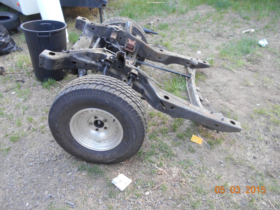 Bare truck frame with rear axle and dually wheels on dirt
