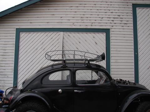 1964 Volkswagen Beetle - A black 1964 Volkswagen Beetle with a roof rack is parked in front of a white wooden garage door.