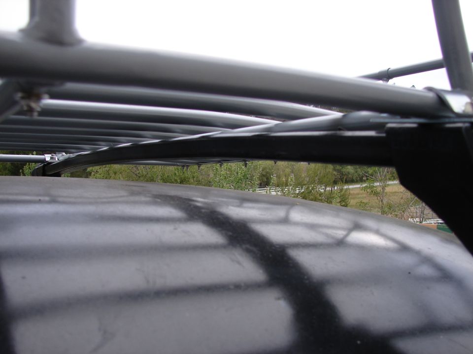 Close-up of a car's roof rack, showing metal bars and straps over the dark roof